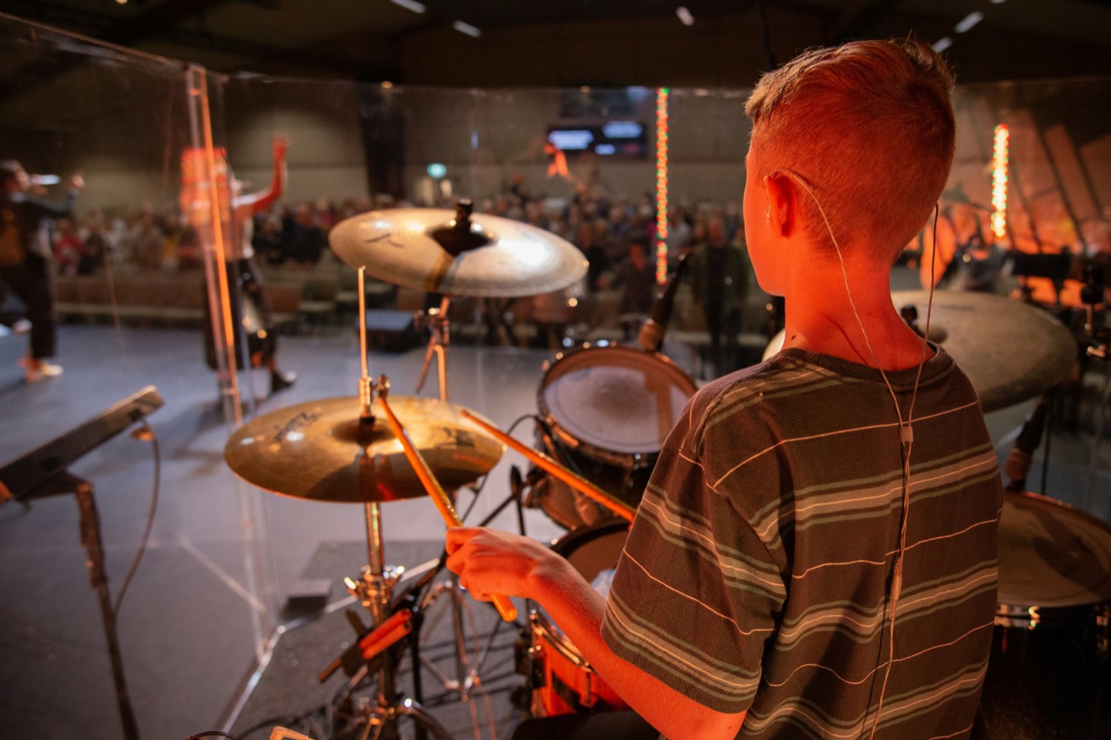 A student performing on the Twelve Tone Music School stage in Glenview, IL during a student recital, with families watching from the audience.